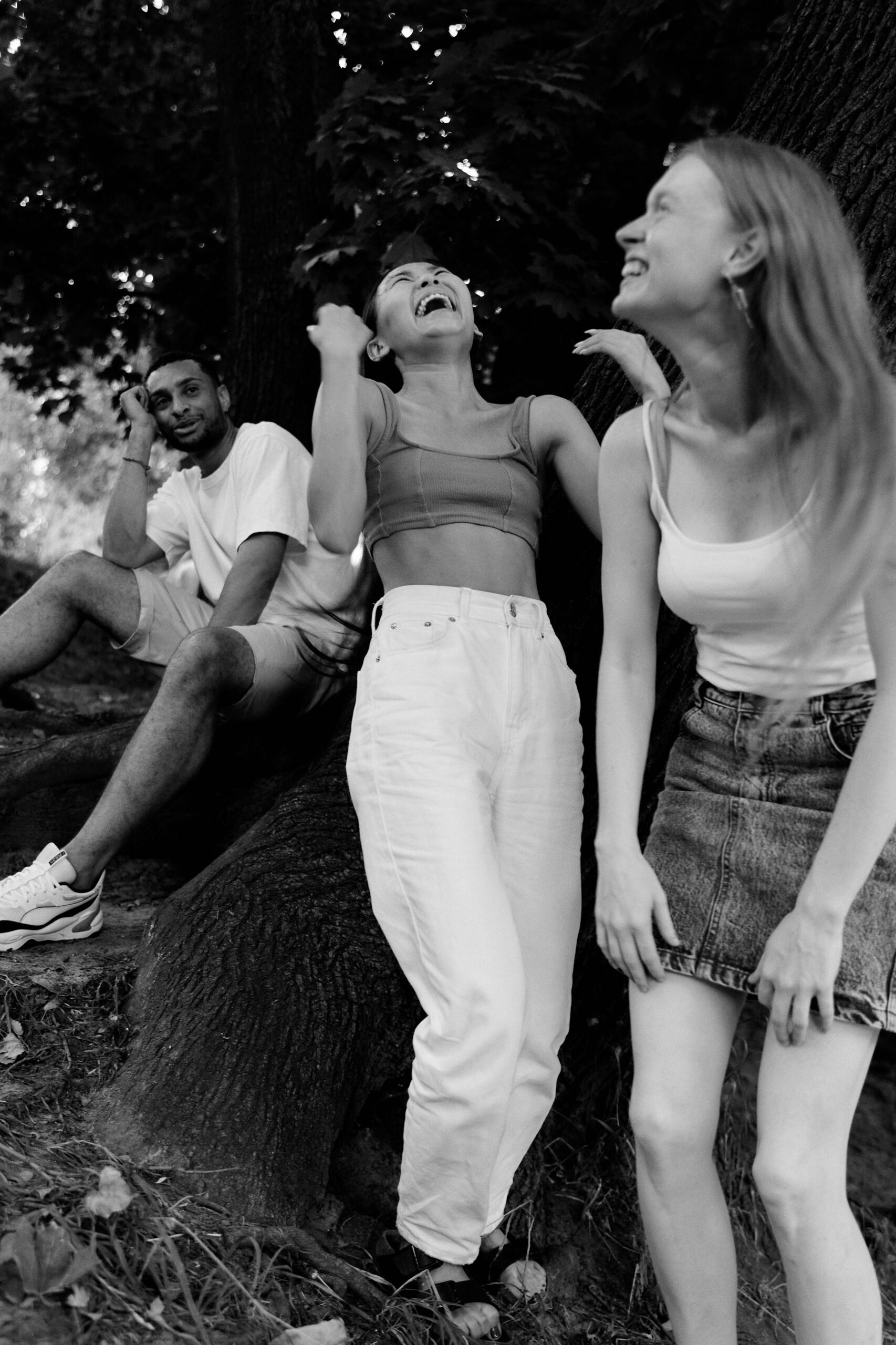 A group of friends sharing a joyful moment outdoors, captured in black and white.