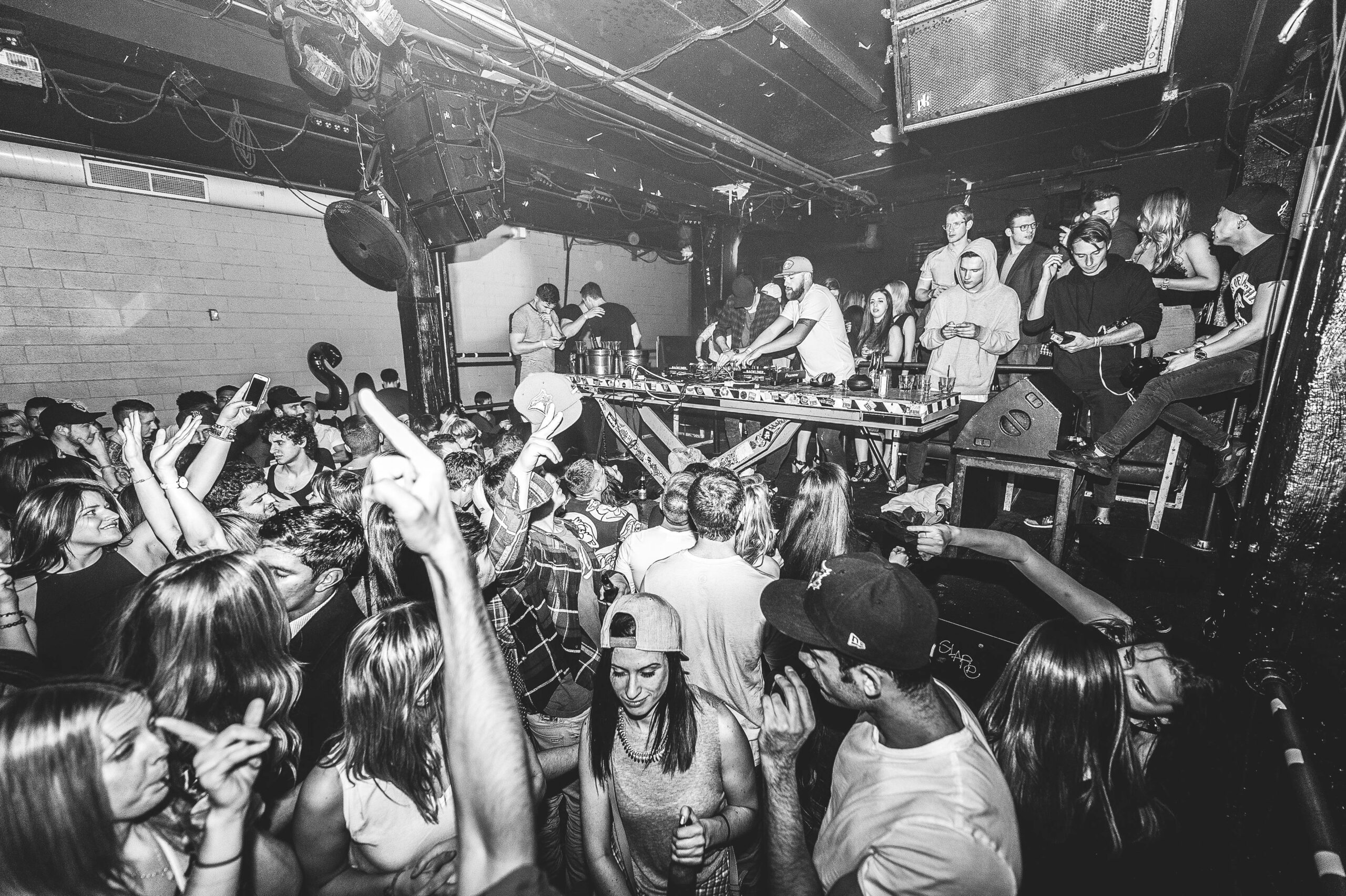 Vibrant nightclub scene with DJ and dancing crowd enjoying live music.