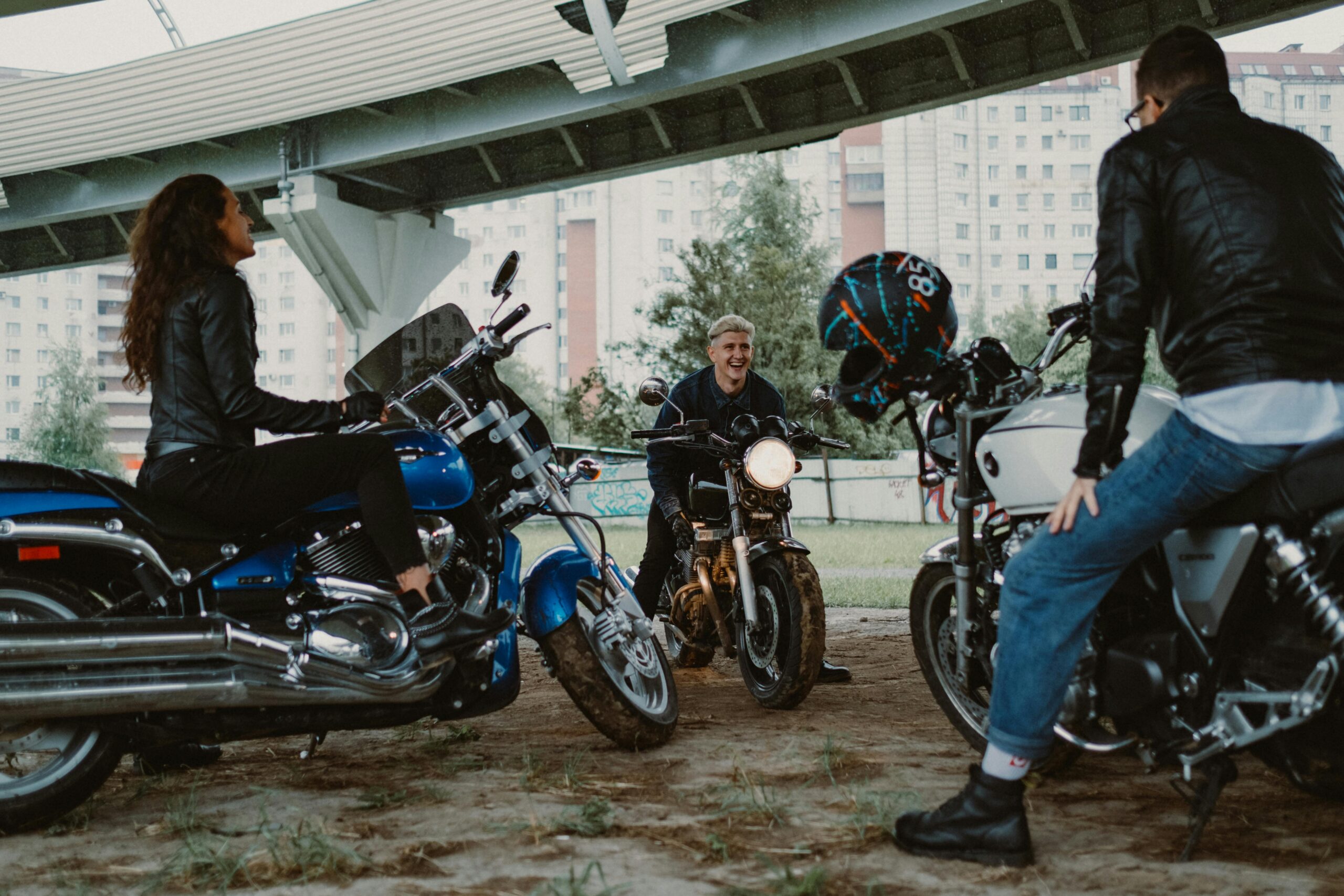 A group of bikers gather under a bridge, enjoying the camaraderie and sharing stories.